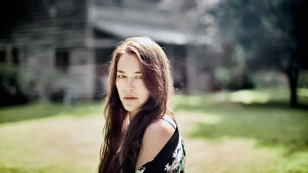 Rachael Yamagata outdoor press photo, long auburn hair, looking over shoulder at camera