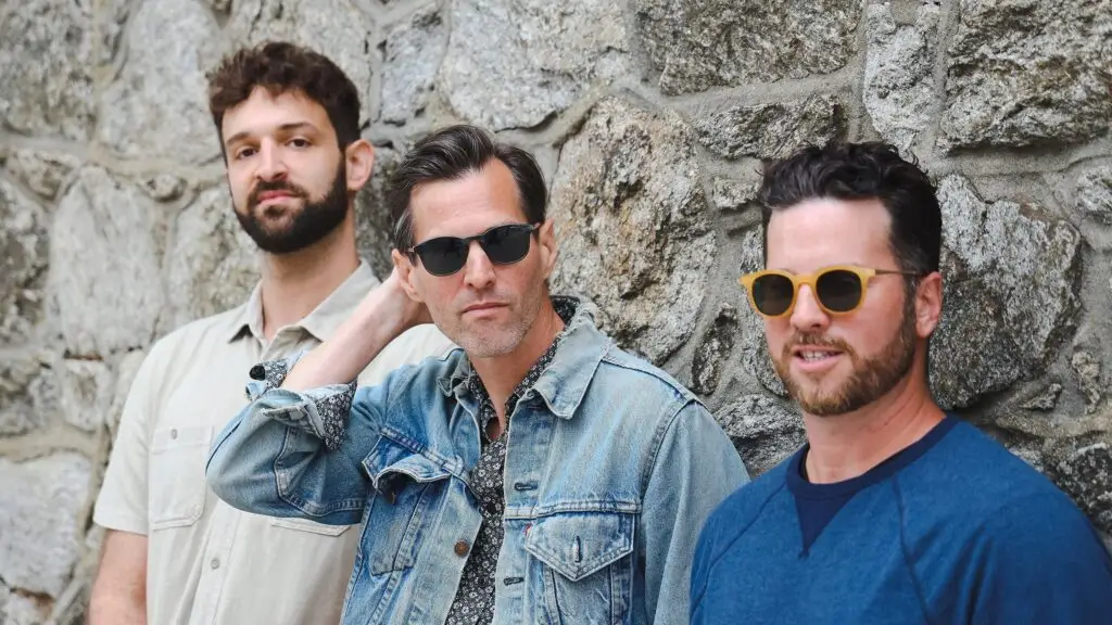 Octave Cat trio — Winderman, Miller, and Patierno — posed outdoors against a stone wall