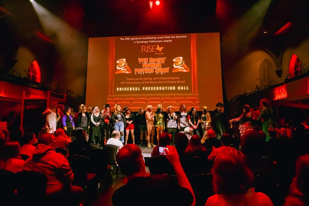 Costumed crowd and performers on stage at Universal Preservation Hall during the RISE Rocky Horror Picture Show fundraiser