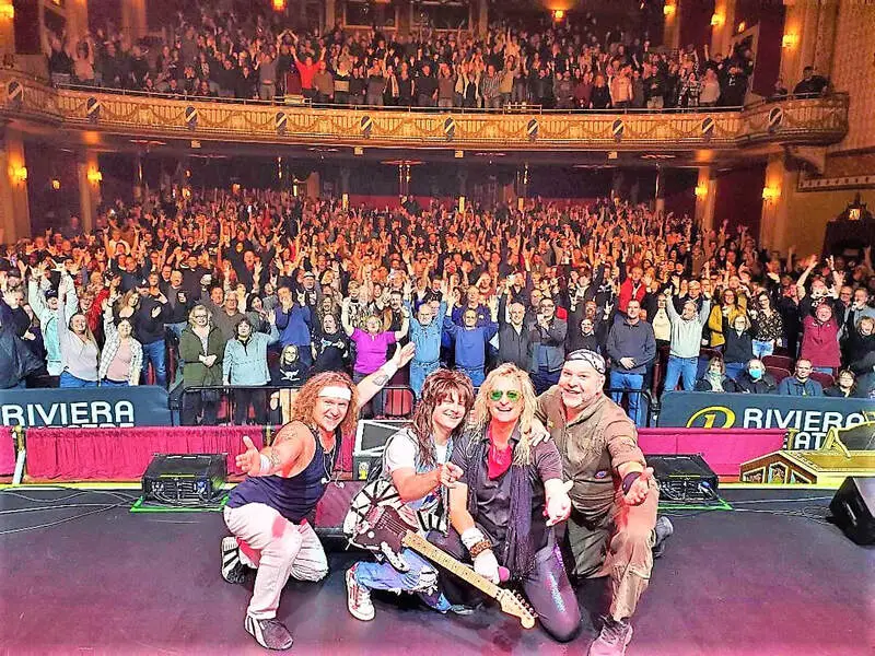 Romeo Delight performing live at the Riviera Theater, four members in Van Halen-era costumes before a massive sold-out crowd