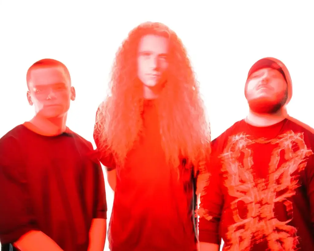 Brotality thrash metal trio in red-toned official press photo, three members posed together