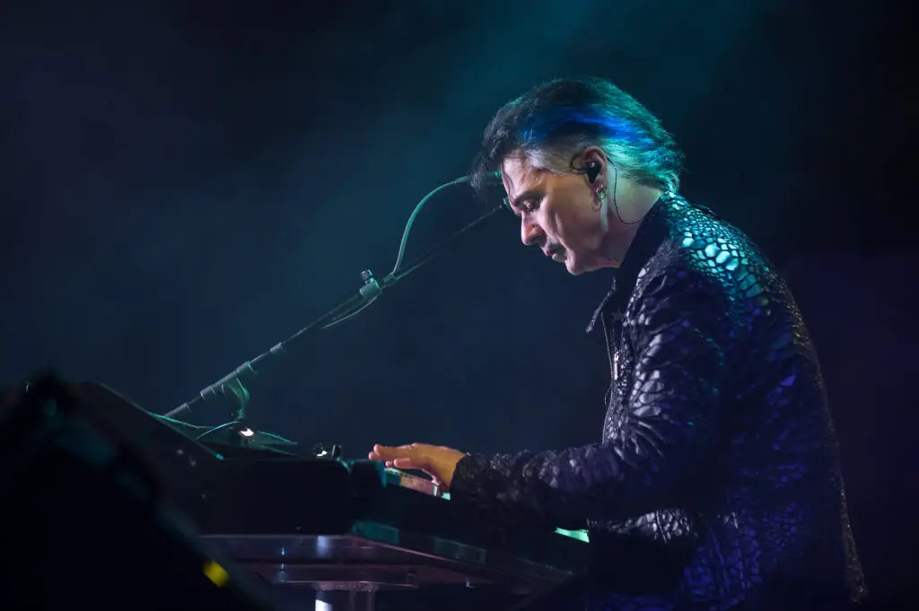 Lawrence Gowan performing at keyboard on stage, blue stage lighting, Strange Animal 40th Anniversary Tour
