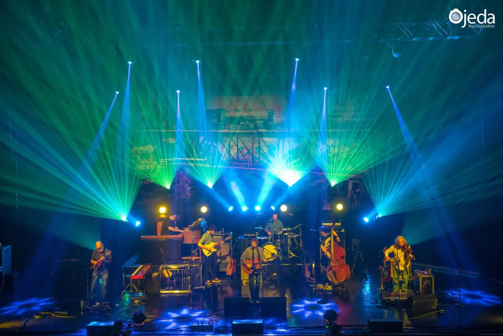 Railroad Earth performing live on stage, full band shot with dramatic green and blue stage lighting