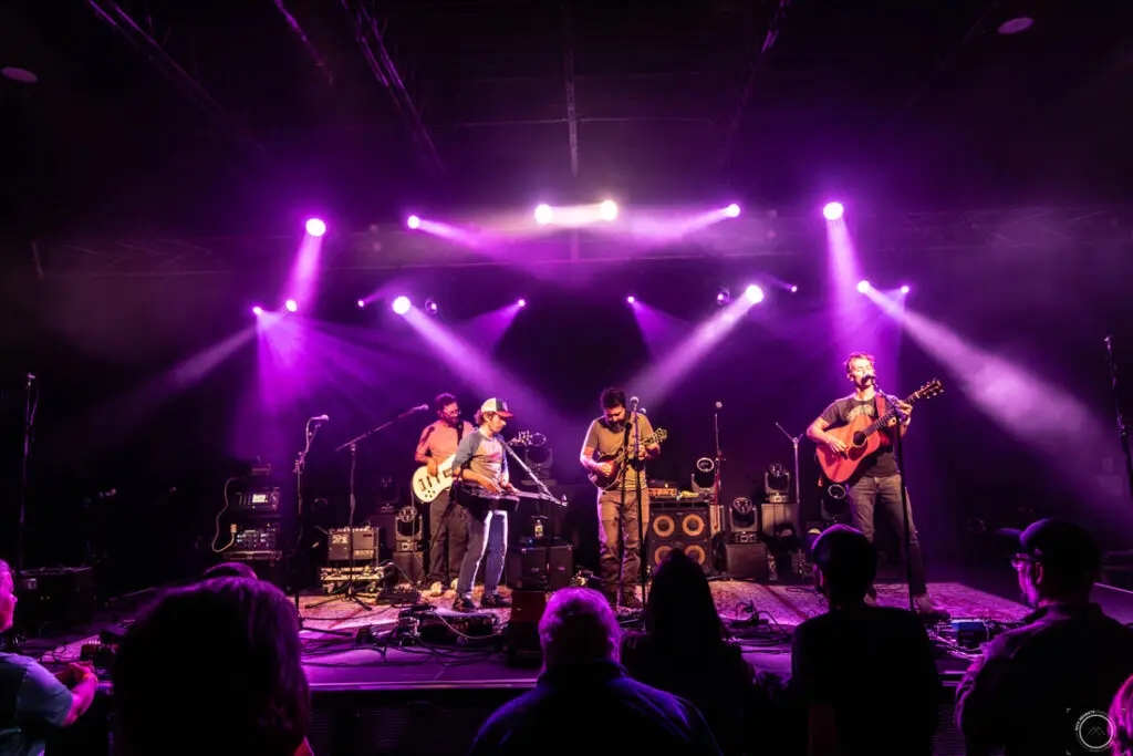 Fireside Collective performing live on stage with purple stage lighting