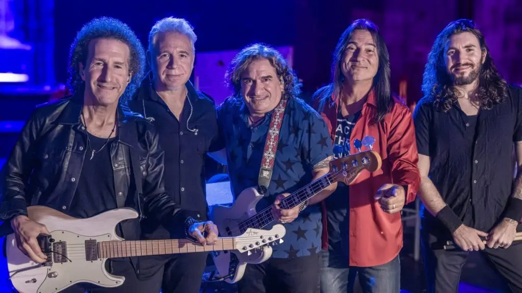 Hugo The Ultimate Journey Tribute performing live, five-piece band with guitars, blue stage lighting