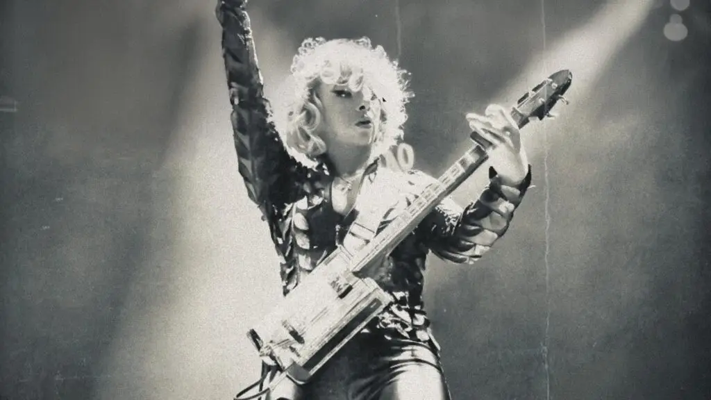 Samantha Fish performing live on stage, playing electric guitar with arm raised under dramatic spotlights
