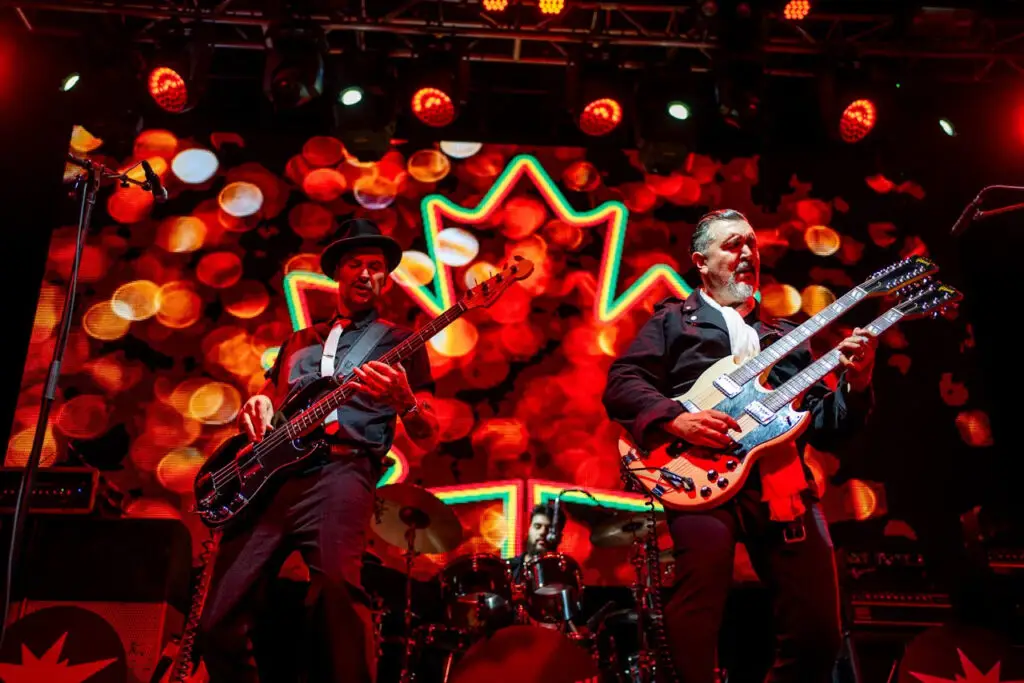 Big Sugar performing live, Gordie Johnson and bassist playing guitars against neon maple leaf LED backdrop