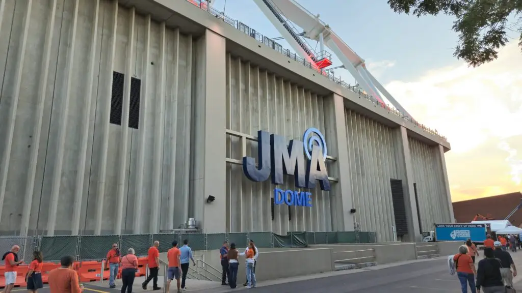 The illuminated JMA DOME signage on the ribbed concrete facade at sunset as fans arrive