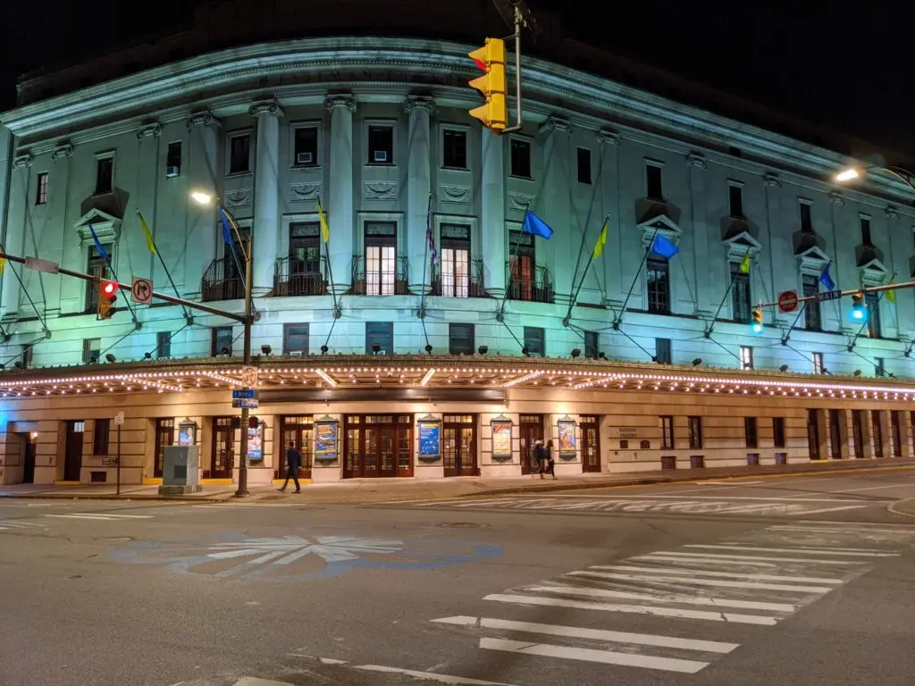 The Eastman Theatre exterior lit at night, with its curved colonnade and illuminated marquee in Rochester
