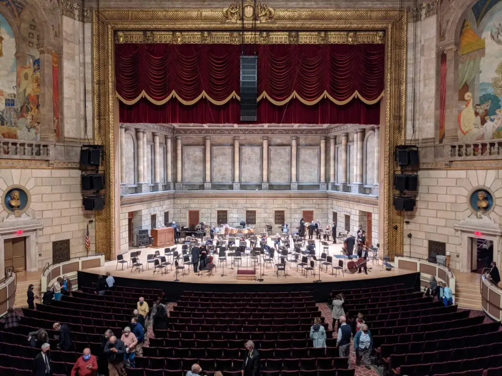 The interior of Kodak Hall at Eastman Theatre, showing the gilded proscenium, murals and orchestra seating