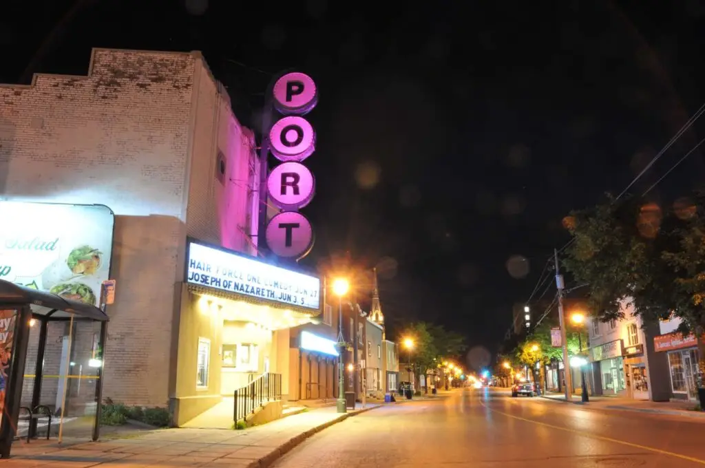The Port Theatre exterior at night in Cornwall, Ontario, with glowing pink PORT neon sign and illuminated marquee