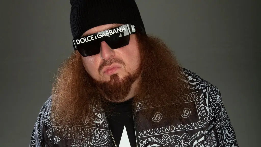 Rittz in official promotional photo with signature long curly hair and Dolce & Gabbana sunglasses
