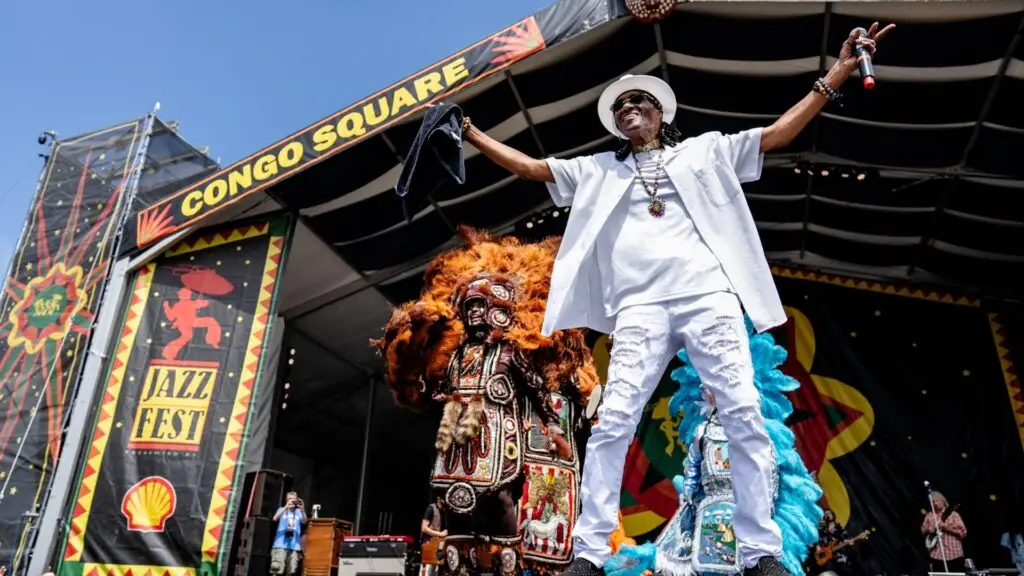 Cyril Neville performing live at Congo Square stage, arms outstretched, New Orleans Jazz Fest