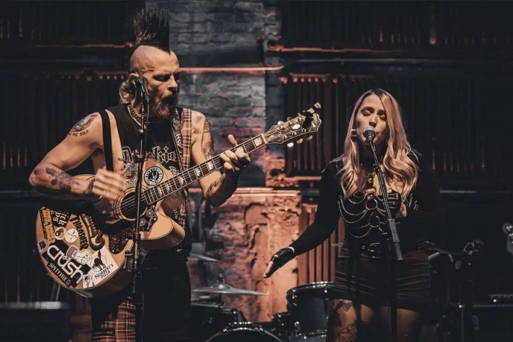 Clover's Curfew performing live, Jameson Jenkins on sticker-covered guitar and Danni Christian singing at Colony Woodstock