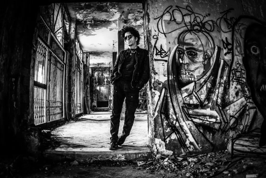 Willie Nile performing live, dark curly hair and sunglasses, black clothing, at Daryl's House Club