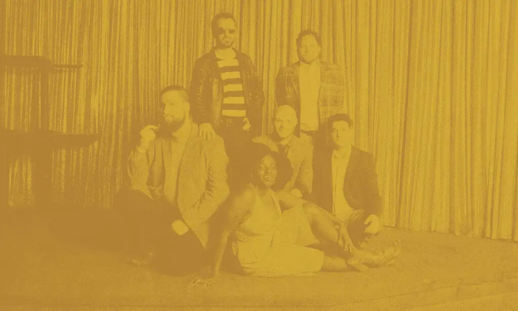 The Big Takeover band posed together in front of a stage curtain for a promotional photo