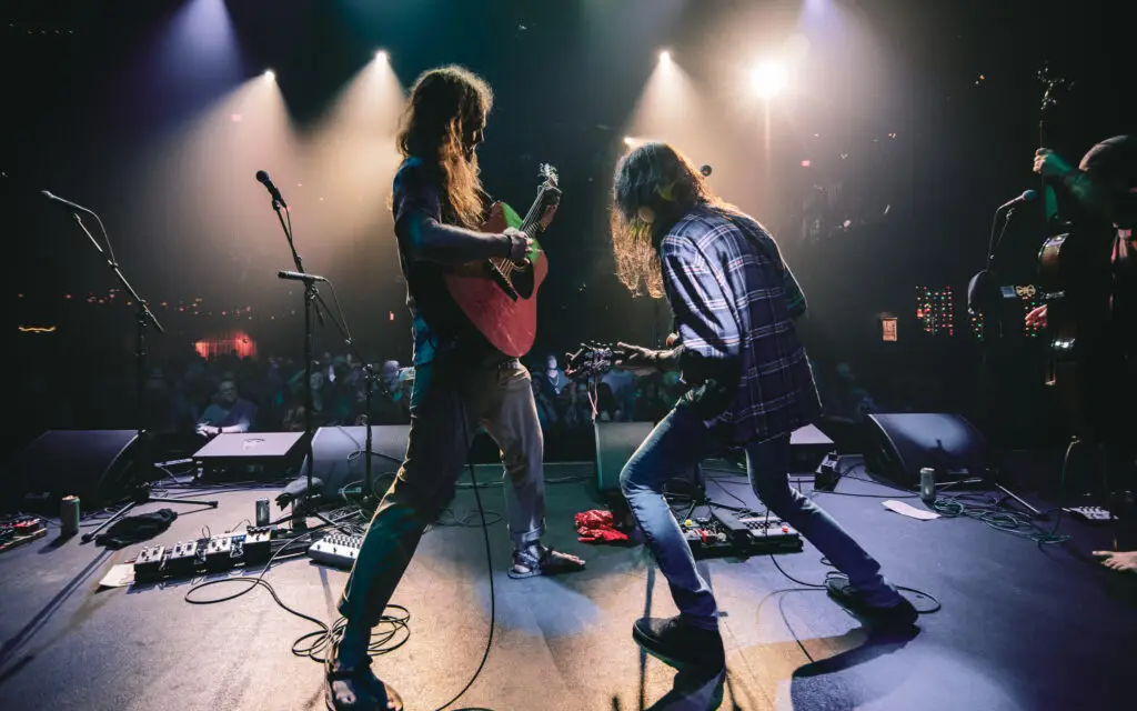 Sicard Hollow performing live on stage, musicians playing string instruments under dramatic concert lighting