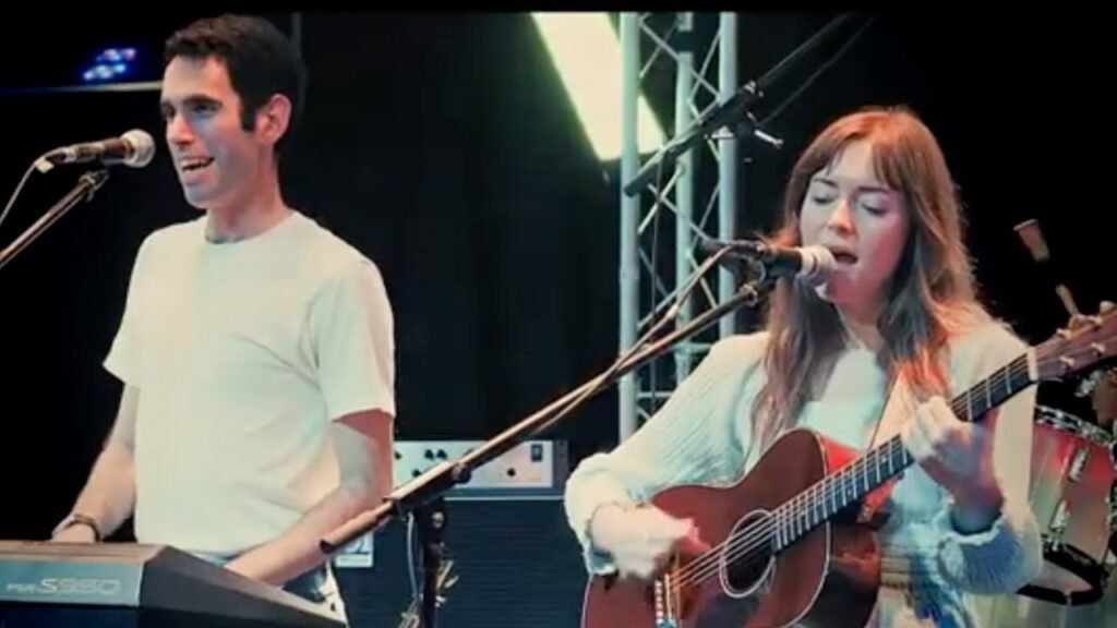 ANTICIPATION tribute performers live on stage — vocalist with acoustic guitar and keyboardist at microphone