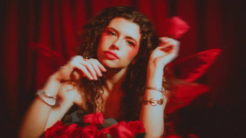 Hannah Wicklund promotional press photo, moody red-toned portrait with roses
