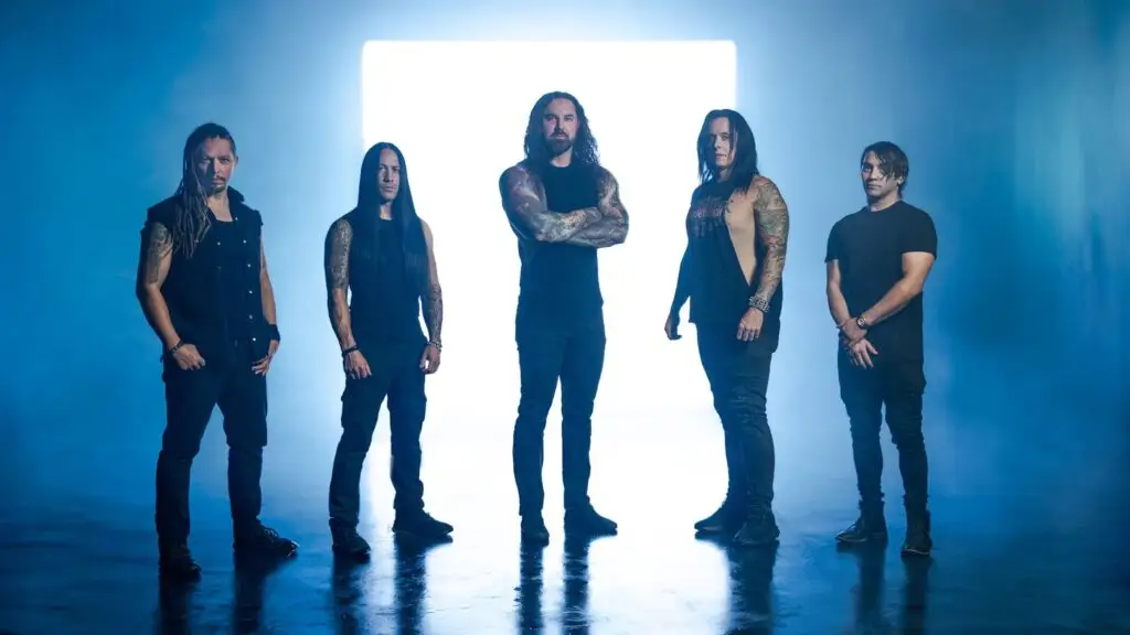 As I Lay Dying metalcore band posed in dramatic blue-lit studio, five members in black attire