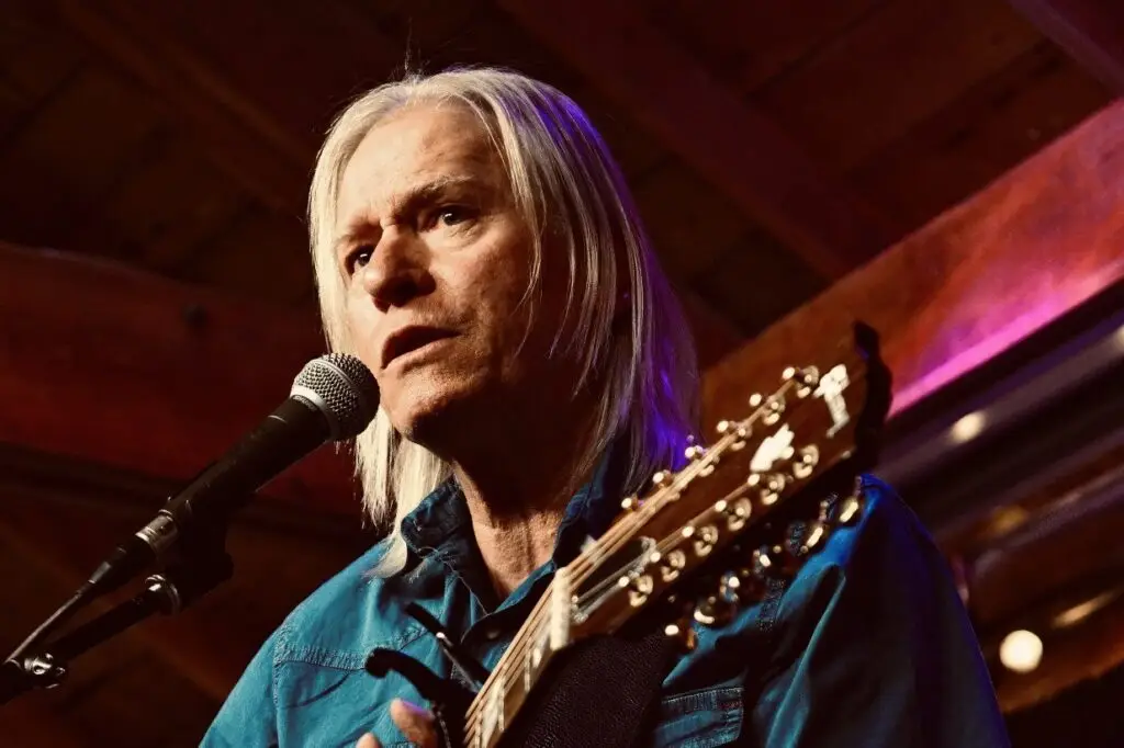 Eric Elison performing live, singing at mic with 12-string acoustic guitar