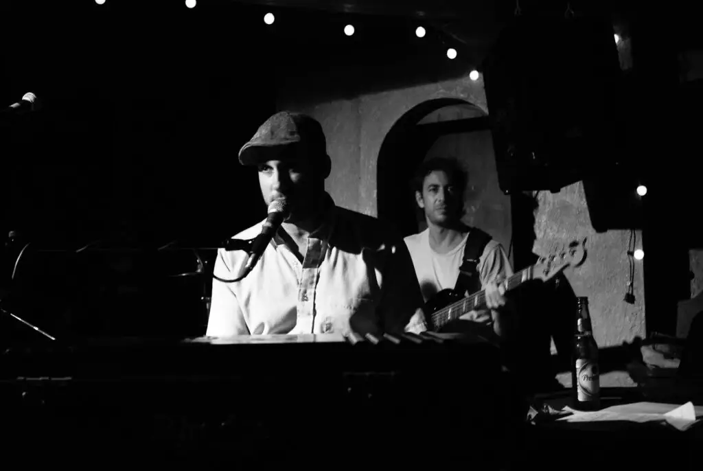 Jonah Smith performing live at piano, leaning into microphone at an intimate club venue