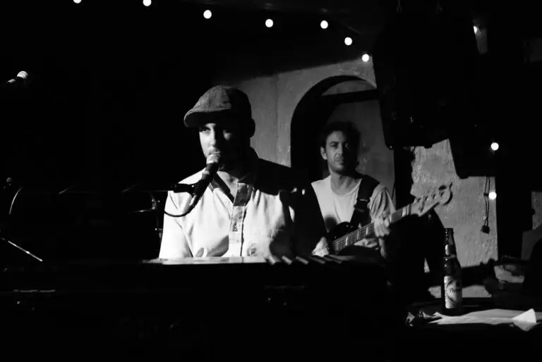 Jonah Smith performing live at piano, leaning into microphone at an intimate club venue