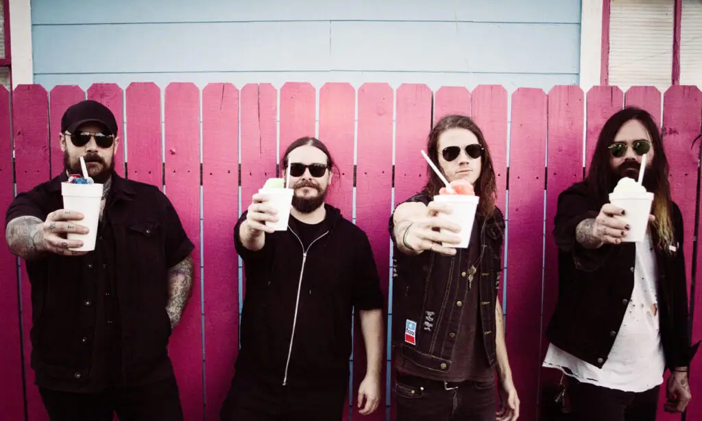 He Is Legend band members posing with snowball drinks against a pink fence, Spinefarm Records press photo