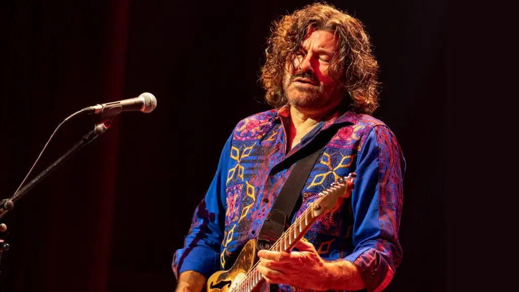 Tab Benoit performing live, playing Telecaster guitar at microphone stand on stage