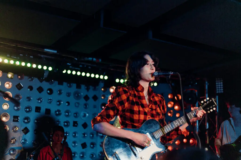 Jackie West performing live on stage, singing and playing electric guitar