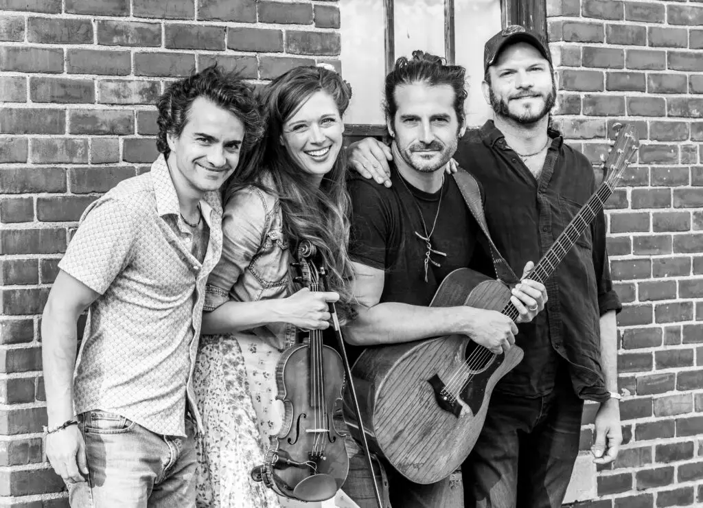 Adam Ezra Group band photo — four-piece folk/Americana group with Adam Ezra on guitar and Corinna Smith on fiddle
