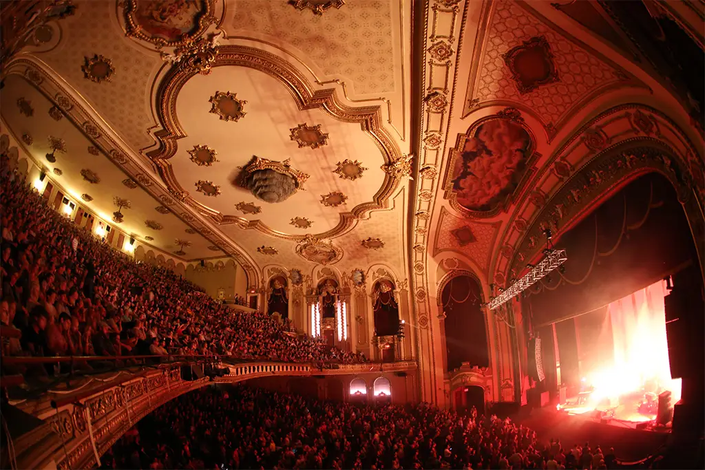 A sold-out crowd under the ornate gilded ceiling of the Palace Theatre in Albany during a concert