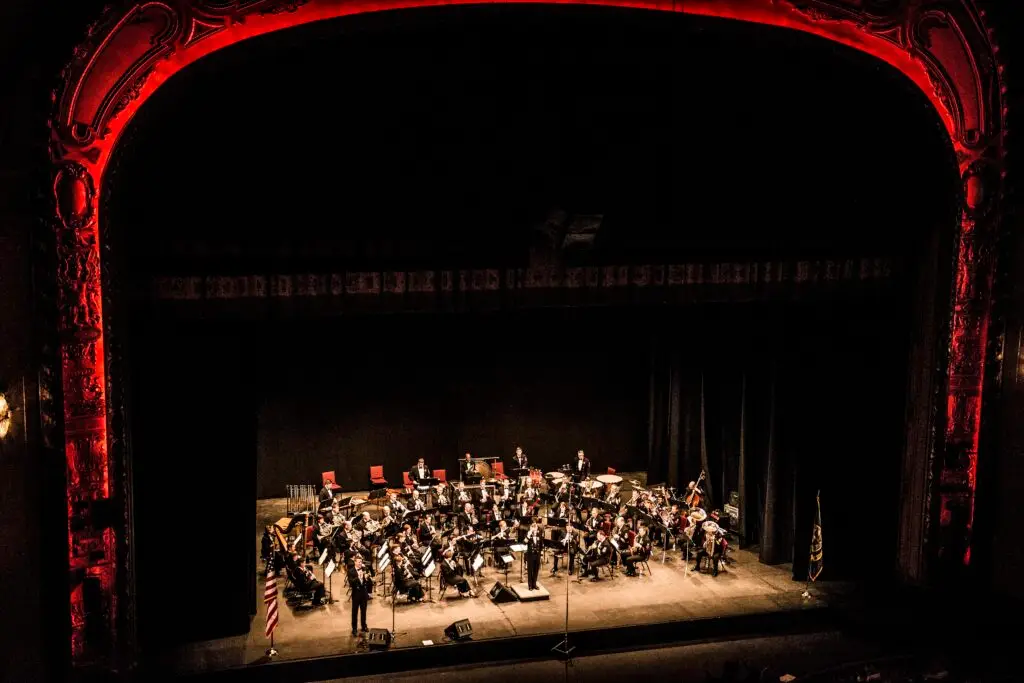 A concert band performs on the Shea's Buffalo stage beneath the ornate gilded proscenium arch