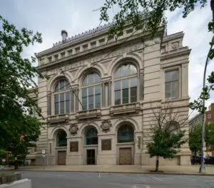 The stone facade of the Troy Savings Bank Building, with Troy Music Hall entrance doors at street level