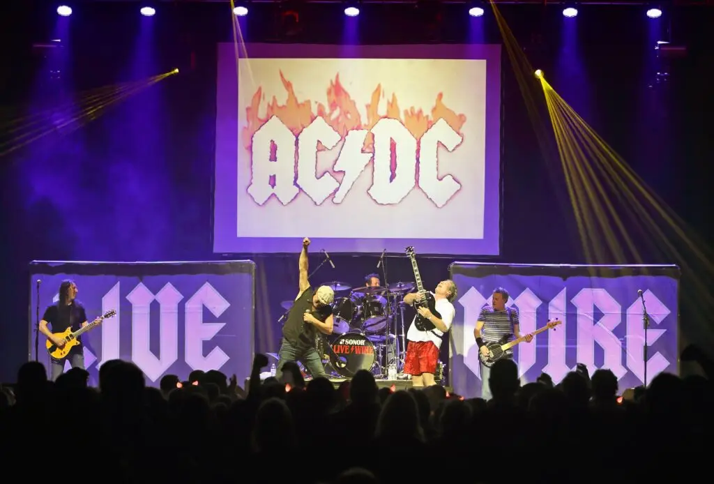 Live Wire AC/DC tribute performing live on stage with crowd, AC/DC backdrop, and LIVE WIRE band banners