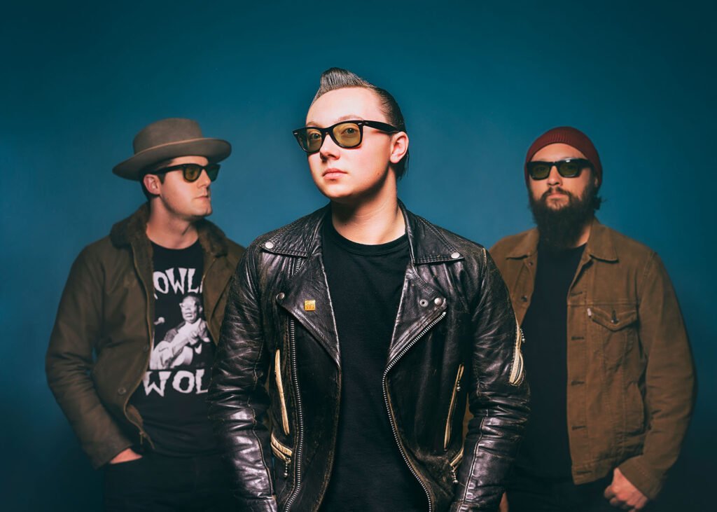 McKinley James and his band in a studio press photo against a teal backdrop