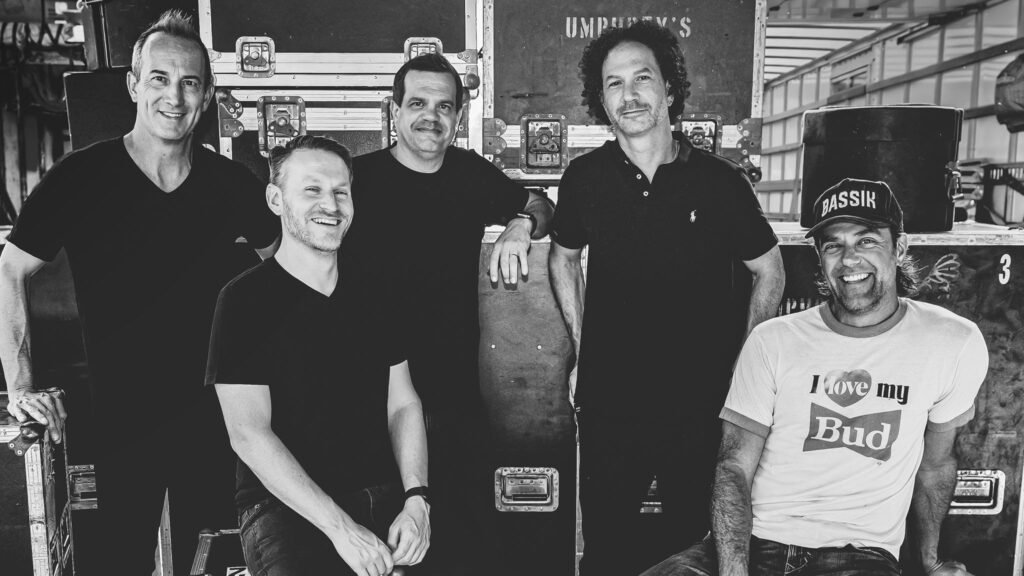 Umphrey's McGee five-piece band posed backstage with road cases, black and white press photo