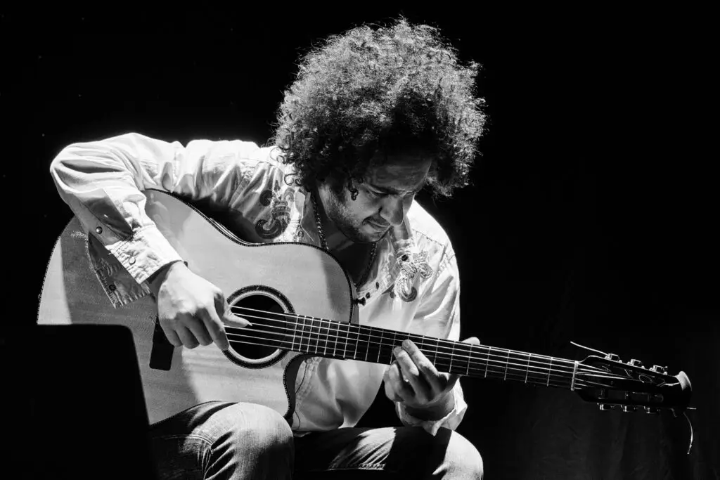 Diego Figueiredo playing classical guitar, dramatic black-and-white live performance