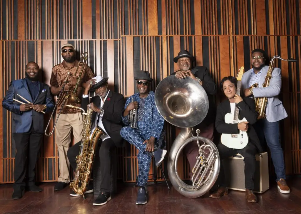 The Dirty Dozen Brass Band seven-piece New Orleans brass ensemble in 2023 studio promo portrait with instruments