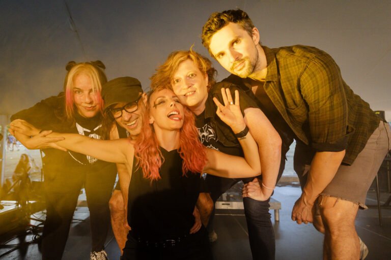 War on Women band photo — five members pose together backstage at a punk festival show