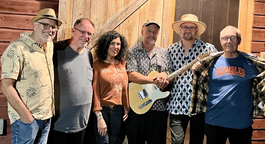 The Shambles band members including Jay Collins and Martee Lebow pose together at a rustic Woodstock barn