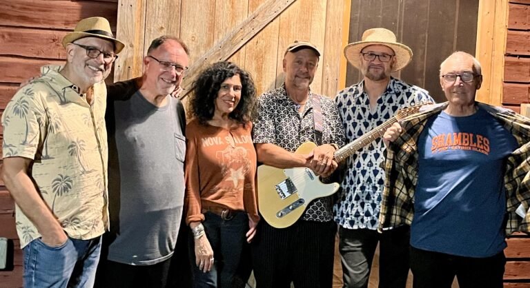 The Shambles band members including Jay Collins and Martee Lebow pose together at a rustic Woodstock barn