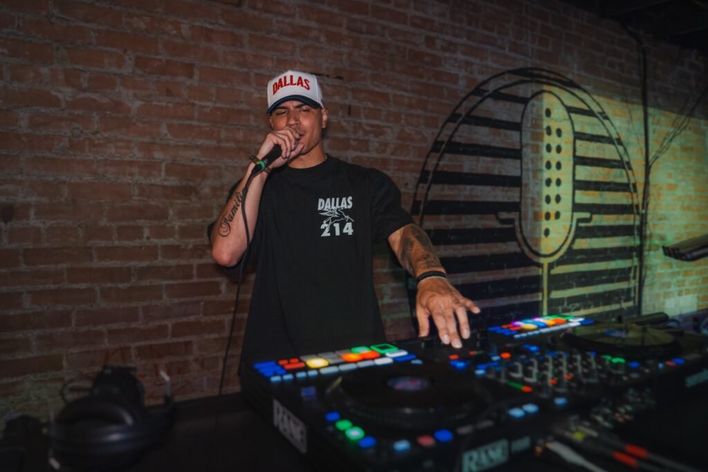 DJ PVLSE performing live at a club venue, on mic at the DJ controller