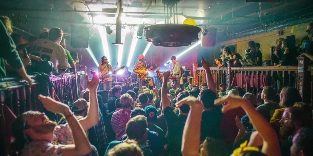 Live band performs on stage at Nietzsche's in Buffalo, NY with crowd arms raised