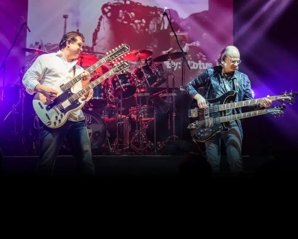 Lotus Land Rush tribute band performing live, with double-neck guitars and large drum kit on stage
