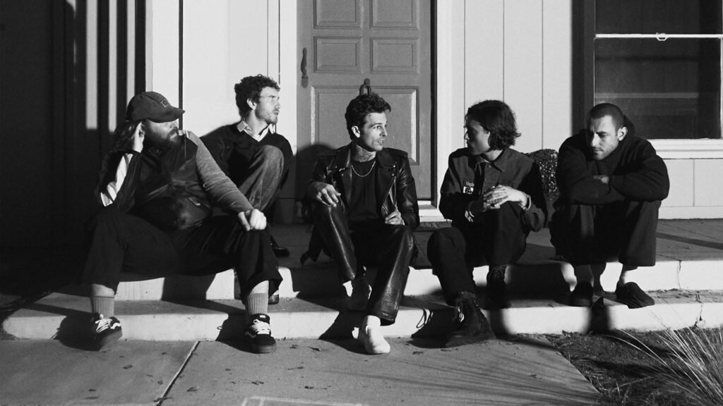 The Neighbourhood band seated on a porch in a black-and-white press photo