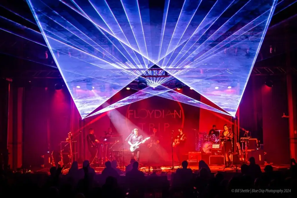 Floydian Trip performing live on stage with full band lineup, dramatic laser fan overhead and Pink Floyd projection backdrop