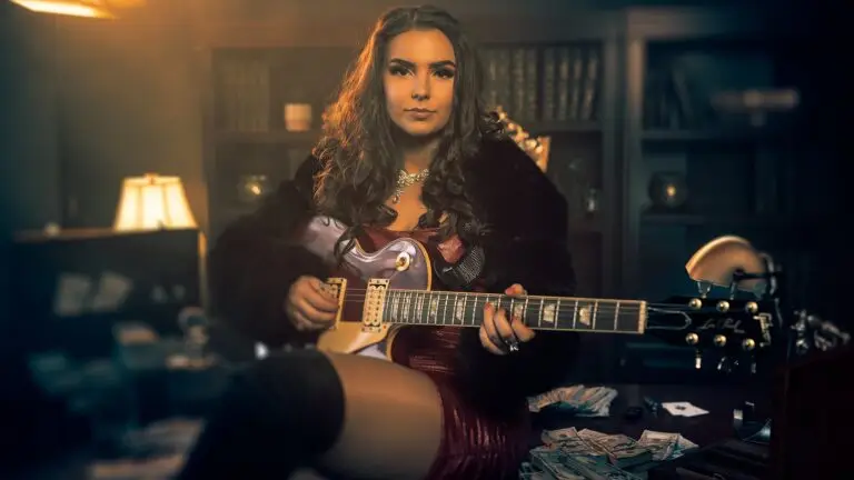 Ally Venable with a Les Paul guitar in a cinematic noir press photo for her Money & Power album