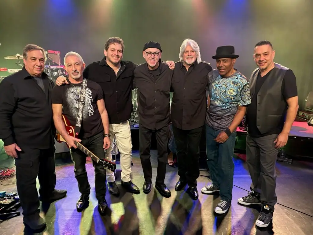 JINGO – The Heart & Soul of Santana, seven-piece Latin-rock band, posed on stage with instruments