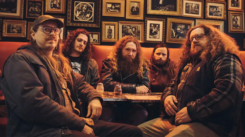 Inter Arma band photo — five-piece Richmond VA metal group posed in a bar booth, 2024 press portrait